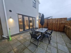 eine Terrasse mit Tisch und Stühlen und einem Zaun in der Unterkunft 4 BR Luxury House. Bike Park Wales. Secure Bike Store. Brecon Beacons in Dowlais