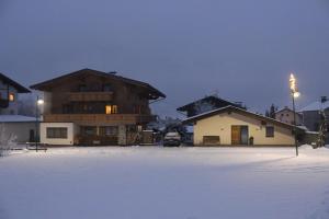 un par de edificios en la nieve por la noche en Haus Jochler, en Ried im Zillertal