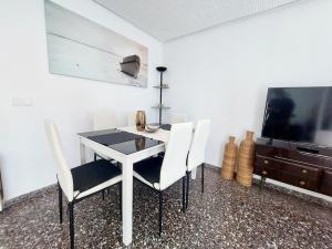 une salle à manger avec une table et des chaises blanches ainsi qu'une télévision dans l'établissement Sunflower Montecarlo, à Santa Pola