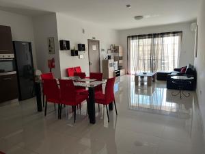 a dining room and living room with a table and red chairs at Claire's Court in Marsaxlokk