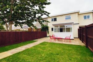 a yard with red chairs and a fence at Family Home in the Charming Coastal Town of Barry in Barry