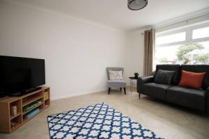 a living room with a couch and a tv at Family Home in the Charming Coastal Town of Barry in Barry