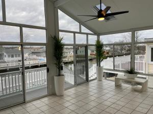a screened in porch with a ceiling fan and plants at Waterfront Home in Brick with Swimming Pool Access in Shore Acres