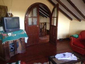 a living room with a tv and an open door at Hotel Campestre los Duraznos in Cucunubá