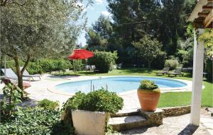 einen Pool in einem Garten mit einem roten Regenschirm in der Unterkunft Nice Home In Sarrians With Wifi in Sarrians