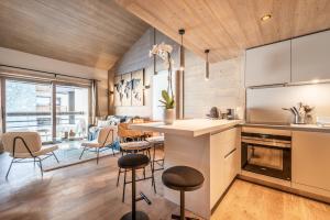 a kitchen with a counter and chairs in a room at Residence Phoenix Courchevel Village - by EMERALD STAY in Courchevel
