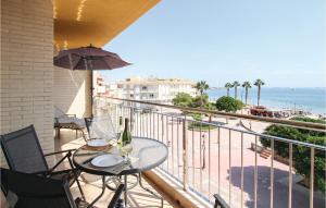 einen Balkon mit einem Tisch, einem Sonnenschirm und dem Meer in der Unterkunft 3 Bedroom Beautiful Apartment In Los Alczares in Los Alcázares