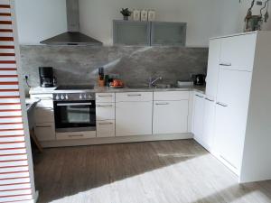 a kitchen with white cabinets and a sink at Butze Ferienapartment in Büsum