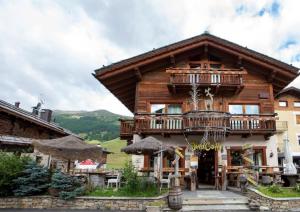 a large wooden house with a balcony and tables at Appartamenti Diva in Livigno