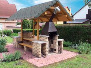 a barbecue with a wooden roof and a stove at Nyaraló Balatonmáriafürdő in Balatonmáriafürdő
