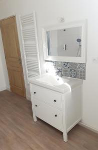 a bathroom with a white sink and a mirror at Au Lutin Pommé - Maison de vacances Bretagne in Mellé