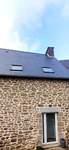 un edificio in pietra con finestra e tetto nero di Au Lutin Pommé - Maison de vacances Bretagne a Mellé