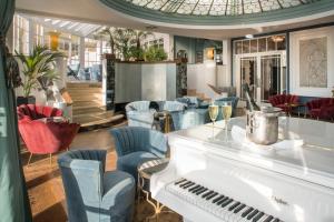 a room with a white piano and chairs at Burgh Island Hotel in Bigbury on Sea