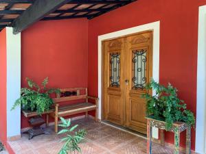 uma porta de madeira numa parede vermelha com dois vasos de plantas em Aldeia Parque Pousada Rural em São Roque