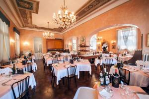 un restaurante con mesas y sillas blancas y una lámpara de araña en Hotel Maderno en Toscolano Maderno