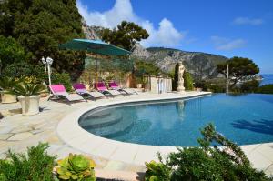 uma piscina com cadeiras e um guarda-sol em Luxury Villa Panorama 5BD 5 BATH em Èze