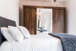 a bedroom with a bed with white sheets and a chandelier at Bryan Street Apartments in Ballymena