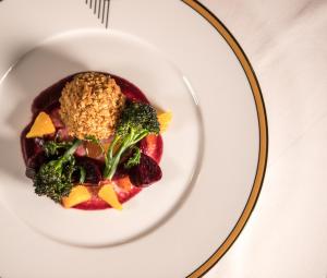 a plate of food with broccoli and fruit on a table at Burgh Island Hotel in Bigbury on Sea