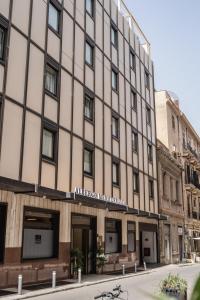 un grand bâtiment situé dans une rue en face d'un bâtiment dans l'établissement Hotel Mediterraneo, à Palerme