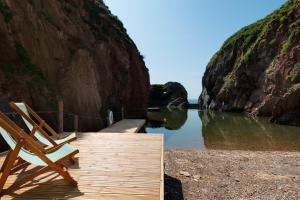 two chairs sitting on a dock next to the water at Burgh Island Hotel in Bigbury on Sea