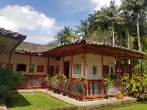 une maison dans un jardin avec une terrasse couverte dans l'établissement Hostal Rio Arabia - Valle De Cocora HOTEL, à Salento