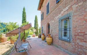 un edificio de ladrillo con sillas y jarrones en un patio en Cozy Home In Castiglione Del Lago With Wifi, en Castiglione del Lago