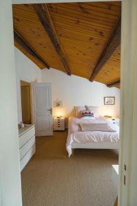 a bedroom with a large bed and a wooden ceiling at A l'ombre du figuier in Longèves