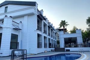 a large white building with a pool in front of it at MİYAS LUXURY HOTEL in Kemer