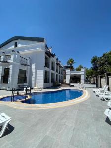 a swimming pool in front of a building with lounge chairs at MİYAS LUXURY HOTEL in Kemer