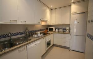 ミハス・コスタにあるBeautiful Apartment In Marbella-el Rosario With Kitchenの白いキャビネット、シンク、冷蔵庫付きのキッチンが備わります。