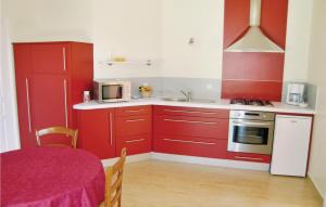 cocina con armarios rojos, fregadero y mesa en 1 Bedroom Awesome Home In Carolles, en Carolles