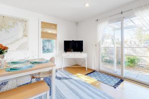 sala de estar blanca con mesa y TV en Modern Beach & Town Getaway en Falmouth