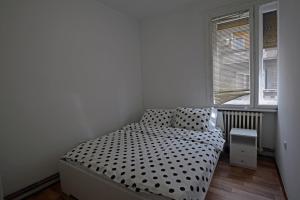 um pequeno quarto com uma cama com lençóis de bolinhas em Apartman Aleksandra centar em Belgrado