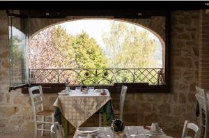 ein Esszimmer mit einem Tisch und einem großen Fenster in der Unterkunft Residenza Collefiorito in Todi