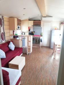 ein Wohnzimmer mit einem roten Sofa und einer Küche in der Unterkunft Bungalow confortable à Vias avec piscine partagée in Vias + 3 Fotos