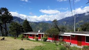 a red and white house with mountains in the background at La Estancia de Runtún Km 7 in Baños