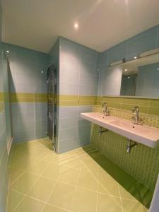 een badkamer met 2 wastafels en groene en witte tegels bij Fijn guesthouse in Noordwijk