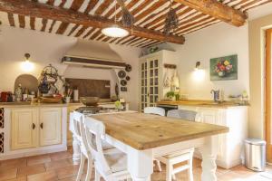 cocina con mesa de madera y sillas blancas en La Douce France en Les Taillades