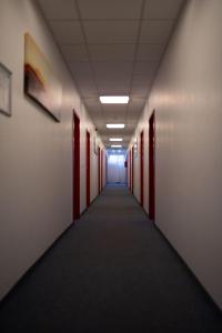 un couloir vide dans un immeuble de bureaux avec portes rouges dans l'établissement RadlStadl - Brauhaus und Hotel, à Kaarst