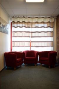 duas cadeiras vermelhas sentadas em frente a uma janela em RadlStadl - Brauhaus und Hotel em Kaarst