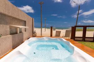 a hot tub on a patio next to the beach at Casa ao mar da Praia de Pirangi por Carpediem in Parnamirim