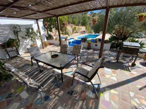 un patio con mesa, sillas y piscina en Casa el saladillo, en Valle de Abdalajís