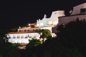 a large white building on a hill at night at Hotel Luci di la Muntagna in Porto Cervo