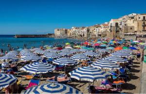 uma praia com muitos guarda-sóis azuis e brancos em Sweet House em Cefalù