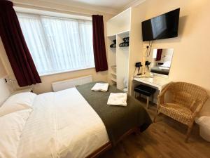 a bedroom with a bed and a desk and a television at Melbourne House Hotel in London