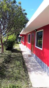 ein rotes Gebäude mit Bürgersteig neben einem Baum in der Unterkunft La Estancia de Runtún Km 7 in Baños
