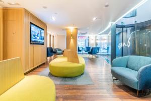 a waiting room with a yellow chair and chairs at Hotel Indigo Madrid - Gran Vía by IHG in Madrid