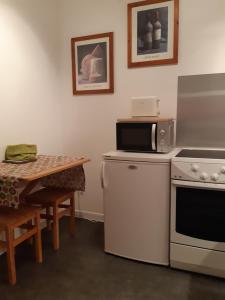 a kitchen with a stove and a microwave and a table at Le BUBELE au coeur du centre médiéval et vignoble in Ribeauvillé