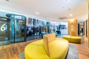 a lobby with a yellow couch and chairs at Hotel Indigo Madrid - Gran Vía by IHG in Madrid