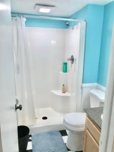 La salle de bains est pourvue d'une douche et de toilettes blanches. dans l'établissement Lake Front Home Near Peek'n Peak, à Findley Lake